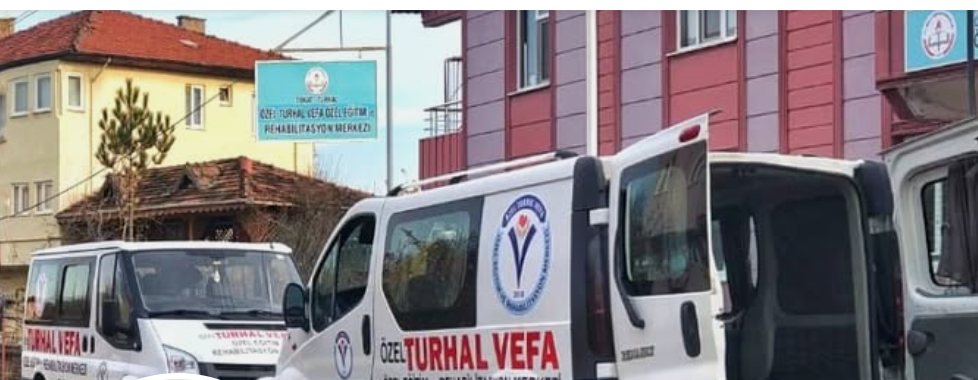 Merkezin önünde park etmiş iki servis minibüsü; binanın üzerinde 'Özel Turhal Vefa Özel Eğitim ve Rehabilitasyon Merkezi' tabelası.